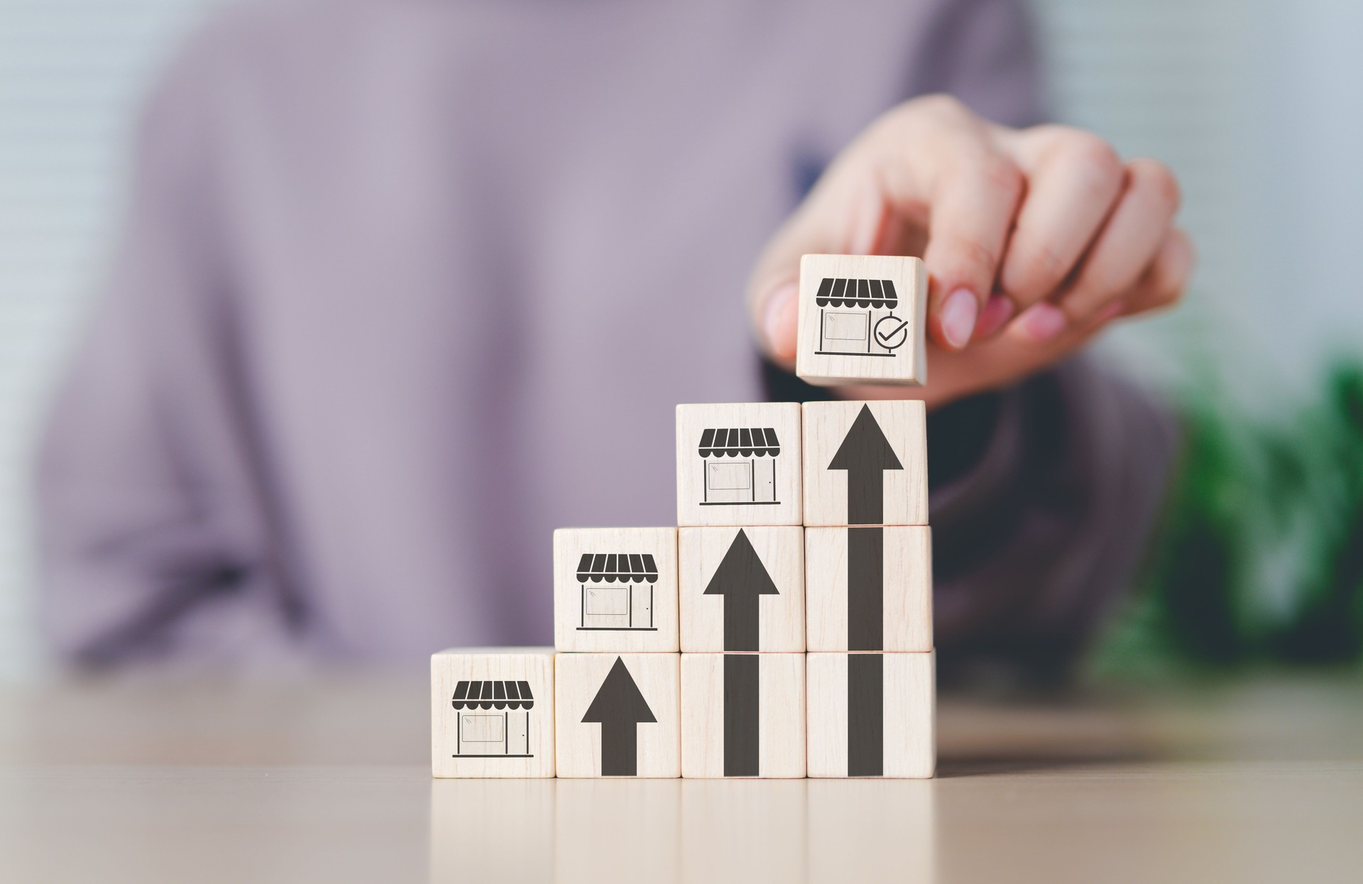 Franchise business growth and expansion concept. Hand stacking wooden blocks with store and arrow icons, franchise business growth, expansion, success entrepreneurship, market development, online shop